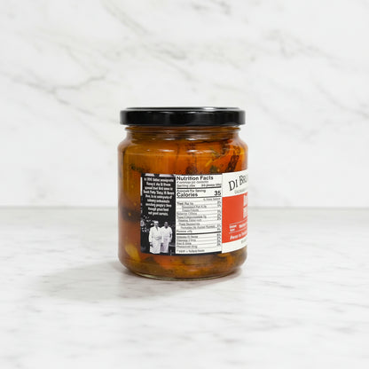 Jar of pickled vegetables on a dark surface with a white tiled wall in the background