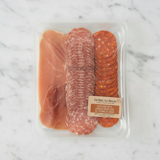 Packaged deli meat assortment with a label on a dark surface