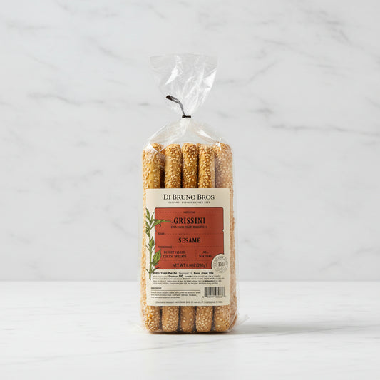 Packaged grissini with sesame seeds on a reflective surface, branded as Di Bruno Bros.