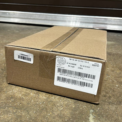 Cardboard box with labels on a concrete floor in front of a metal shutter