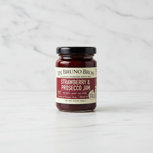 Jar of strawberry and prosecco jam on a black surface with a white background