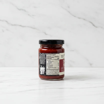 Jar of sauce with a label on a white marble surface