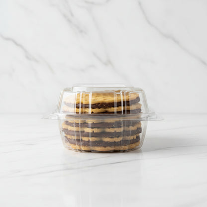 Packaged cookies in a clear plastic container on a black surface with a white background