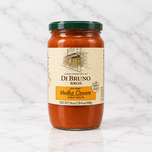 A glass jar of Di Bruno Bros. vodka cream sauce with a dark green lid and a beige label, set against a plain white background.