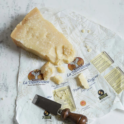 Block of Parmesan cheese with a cheese knife on a branded paper, on a light gray surface.