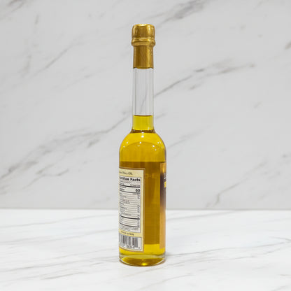 Small bottle of liquid with a gold cap on a dark surface and light gray background