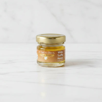 Jar of De Bruno Bros. White Truffle Honey on a dark surface with a light gray background