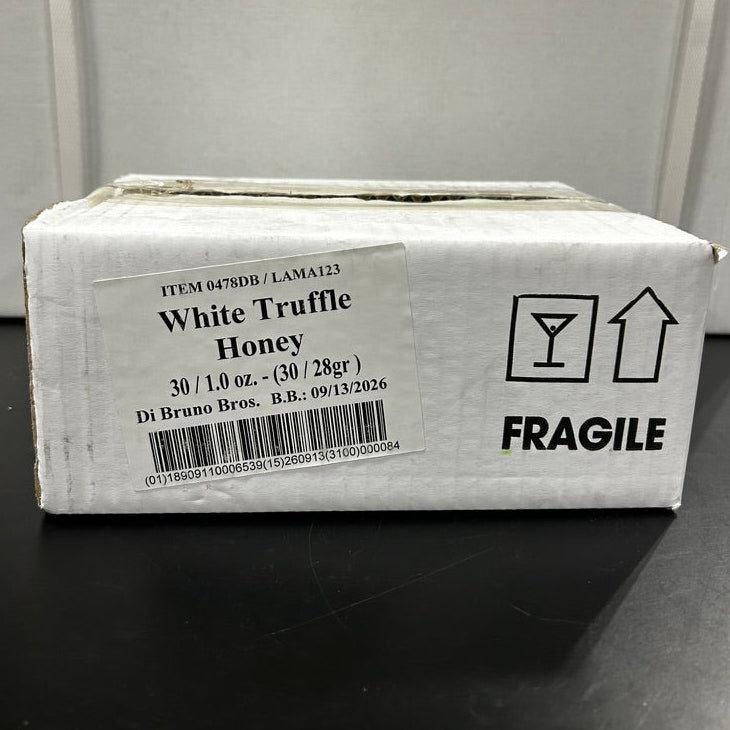 Box of White Truffle Honey with 'Fragile' label on a dark surface