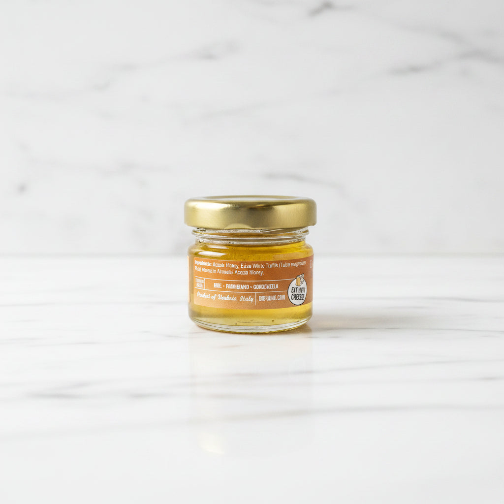 Small jar of honey with a gold lid on a dark surface
