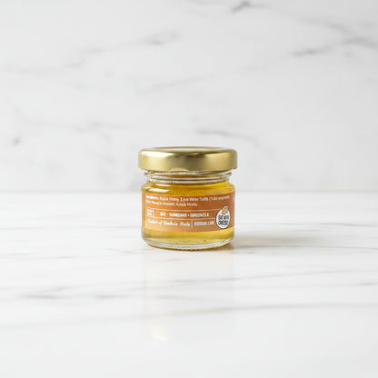 Small jar of honey with a gold lid on a dark surface