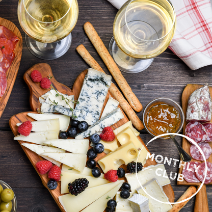 Assorted meats, cheeses, and fruits on a wooden table.