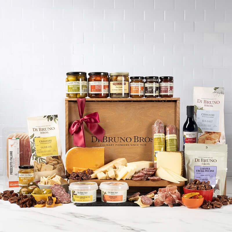 Styled Di Bruno Bros. Extravaganza gift assortment with cheeses, cured meats, jars, crostini, and a branded wooden display crate