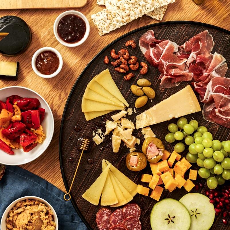 Overhead serving suggestion with assorted cheeses, prosciutto, salami, antipasti, crackers, and fruit