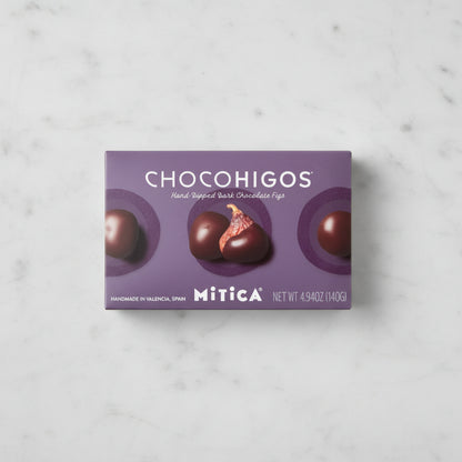 A rectangular box of Chocohigos hand-dipped dark chocolate figs by Mitica, featuring a purple background with four
chocolate-covered figs and the brand name clearly visible.