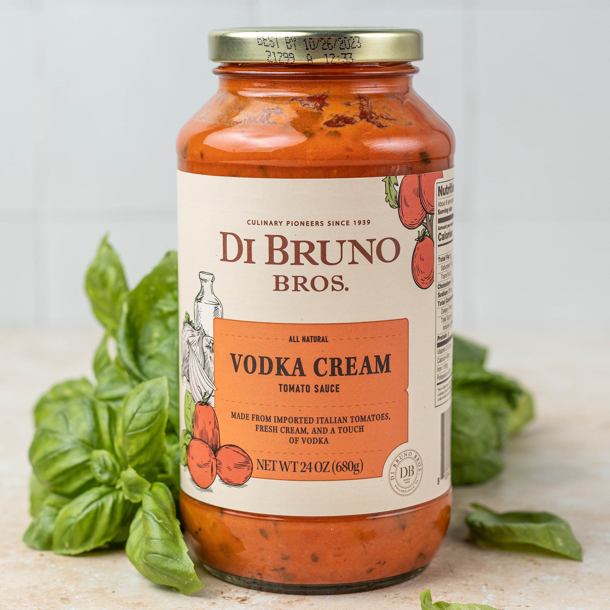 Di Bruno Bros Vodka Cream Tomato Sauce bottle with basil leaves on a light background